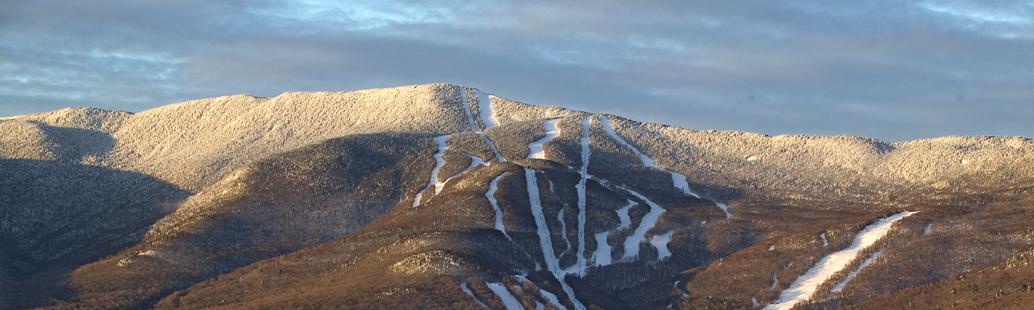 Sun sets over a snow covered ski area mountain range.